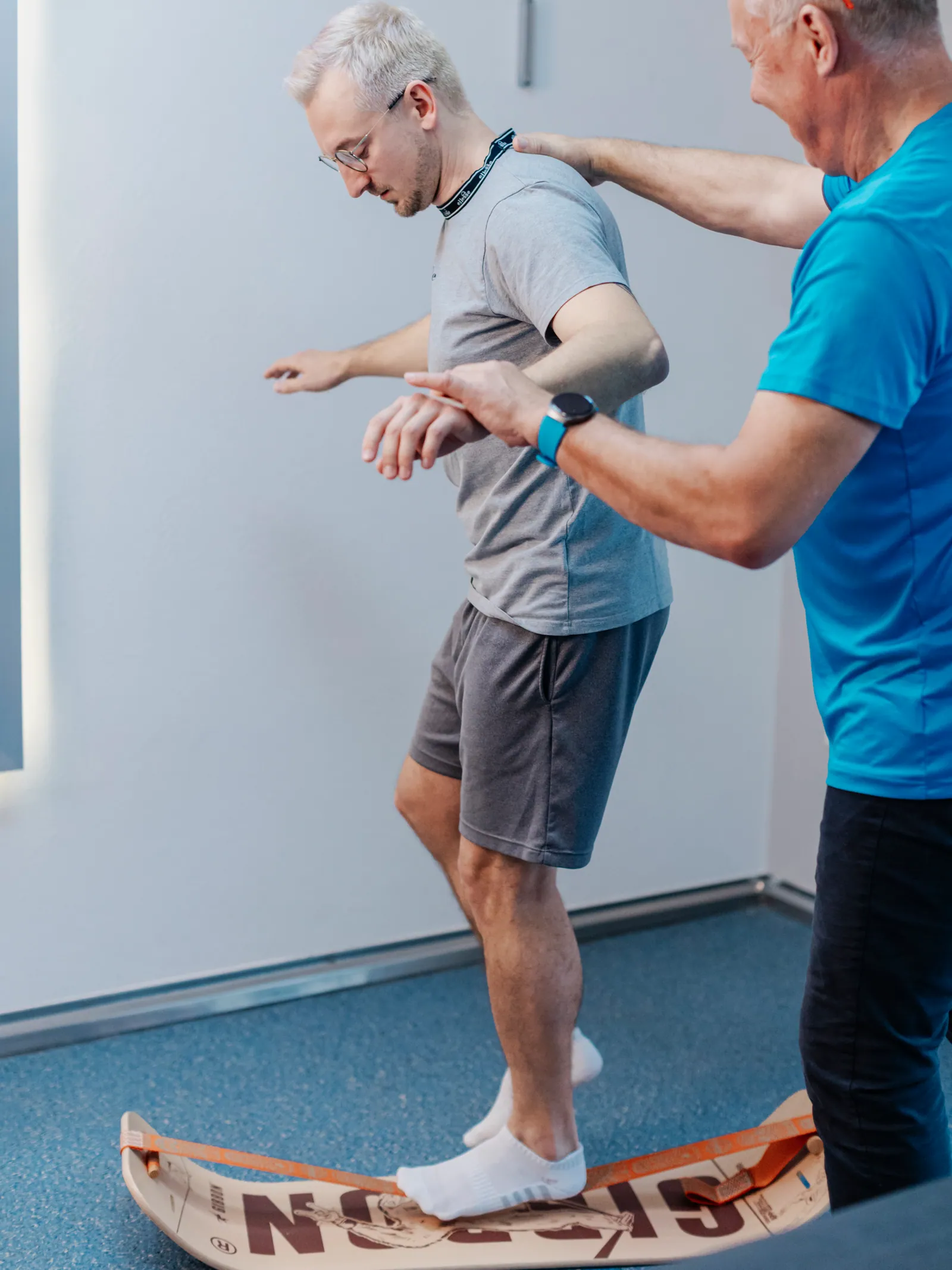 Christian Wolf begleitet einen Patienten beim Gleichgewichtstraining auf dem Balancebrett